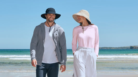 A woman and a man on a beach wearing Solbari sun protective clothing and UPF 50+ hats.
