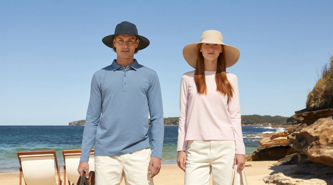 A man and a woman standing on a beach with blue sky behind them wearing Solbari sun hats and UPF 50+ clothing