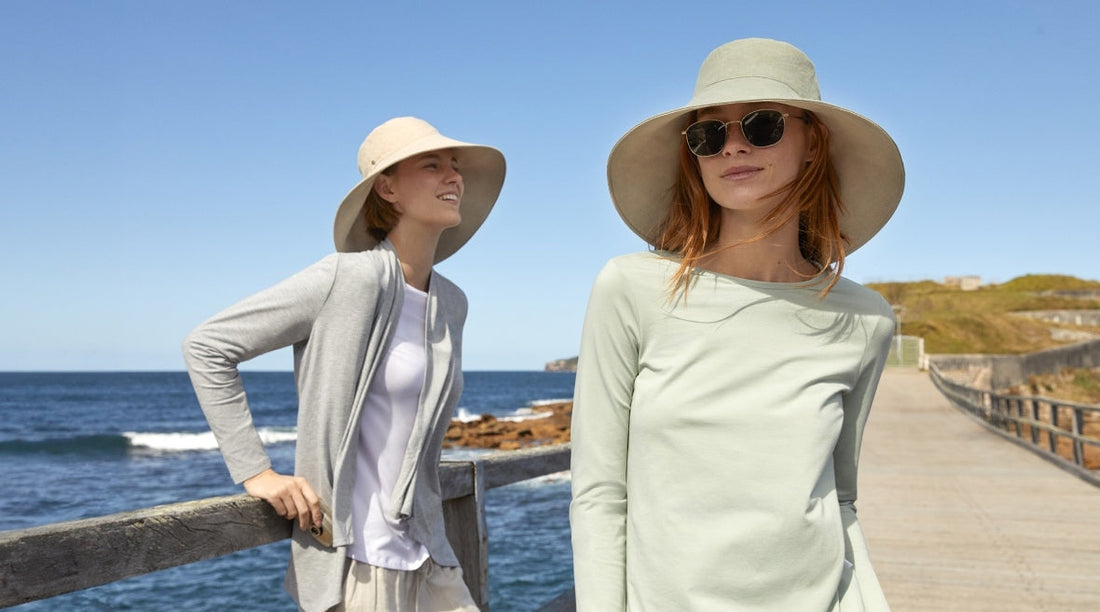 Two women wearing Solbari UPF 50+ sun hats and clothing with the sea and a blue sky behind them