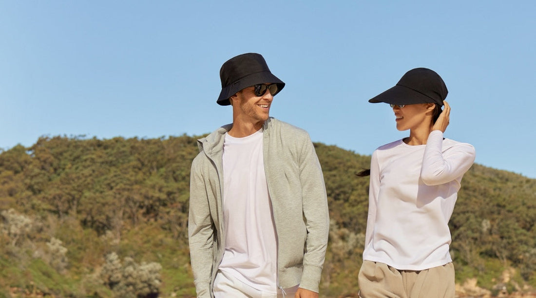 A man and a woman in black Solbari sun hats with a blue sky in the background.