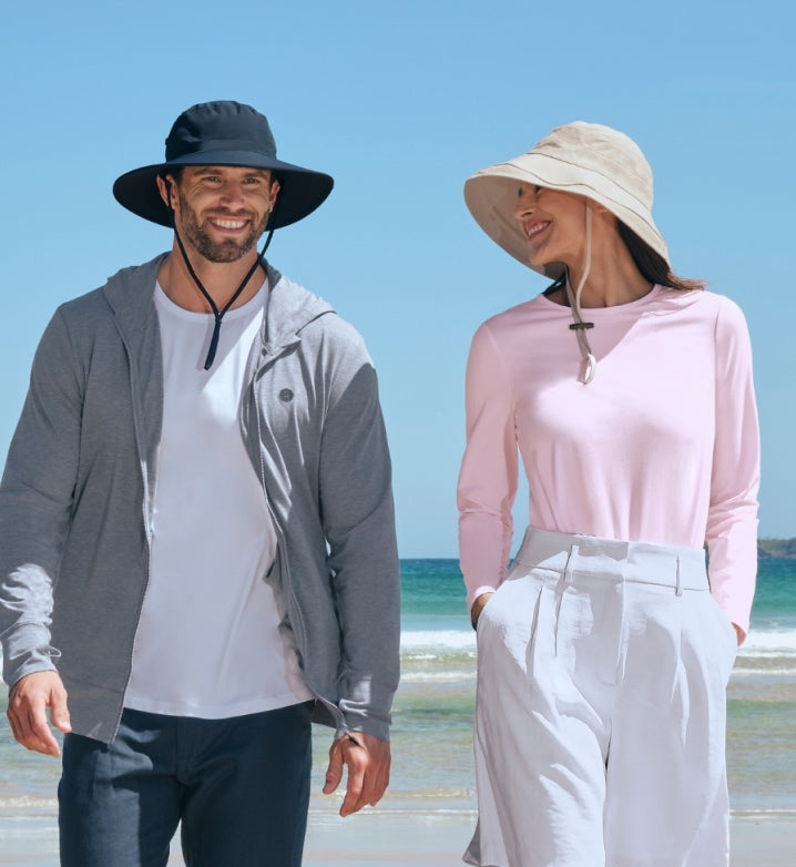 Man and woman wearing Solbari UPF 50+ wide-brimmed sun hats on a beach.