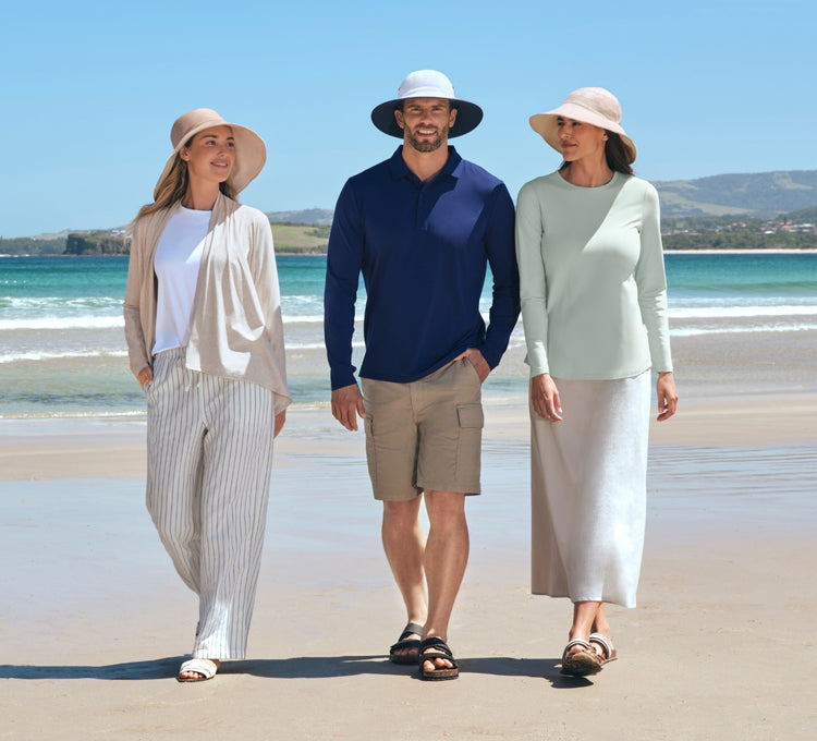Three people standing on a beach with ocean and sky in the background wearing Solbari UPF 50+ sun hats and sun protective clothing.