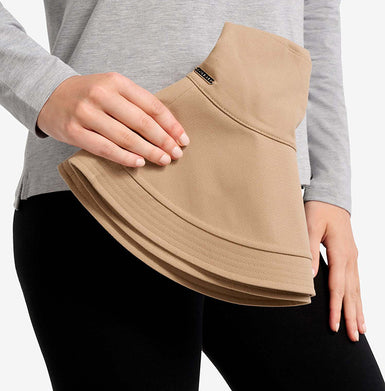 Person holing a beige Solbari hat with a grey top and black pants on a white background.