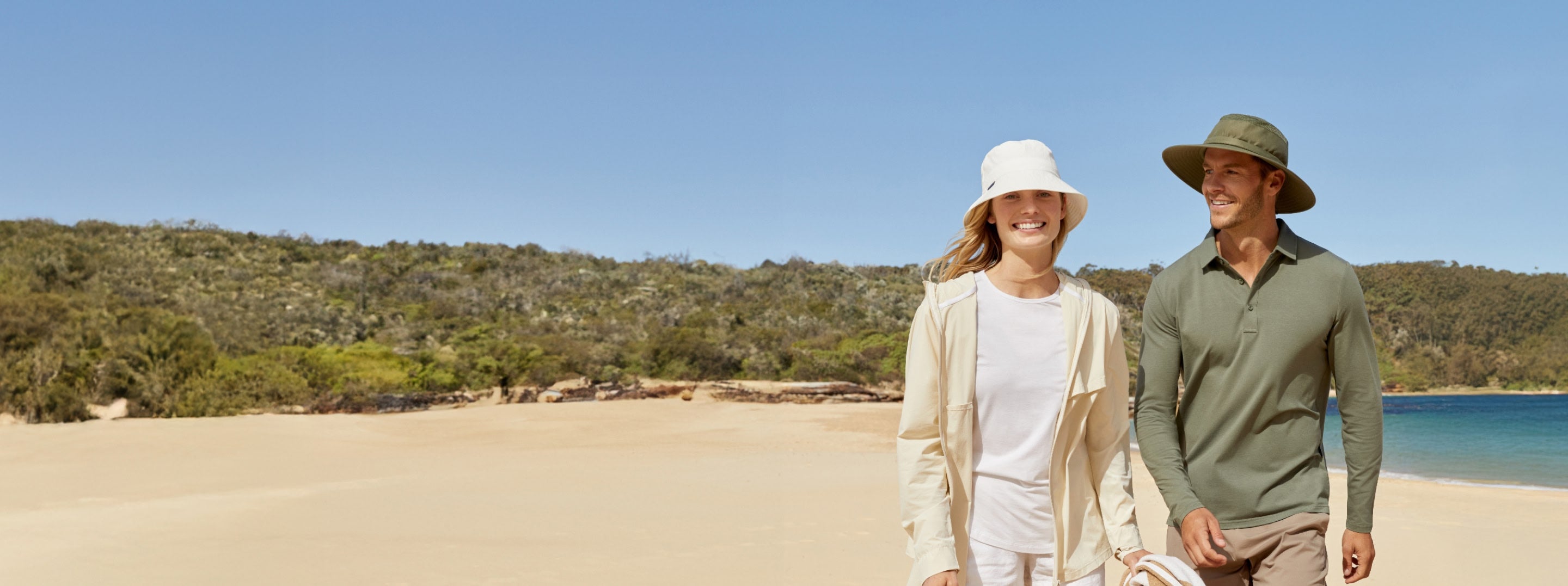 Two people walking on a beach with a scenic background